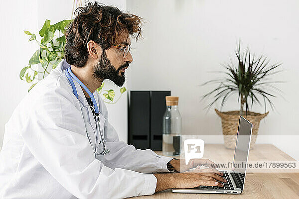 Doctor working on laptop sitting at desk in home office