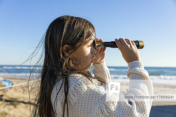 Girl looking through monocular at beach