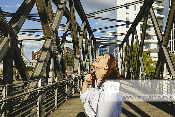 Glückliche Frau mit geschlossenen Augen auf der Brücke