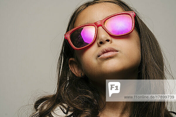 Confident girl wearing sunglasses against gray background