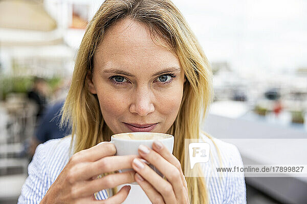 Smiling blond businesswoman holding coffee cup
