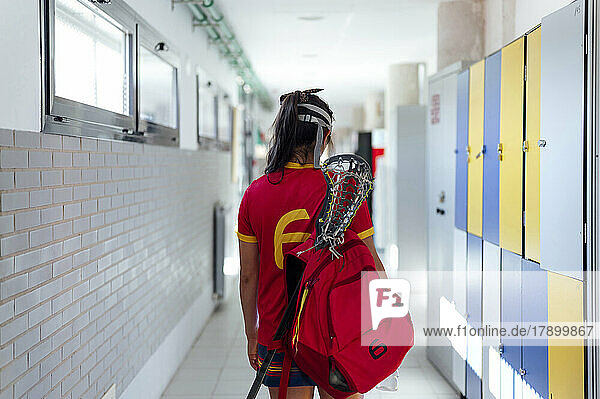 Lacrosse player with backpack walking in locker room