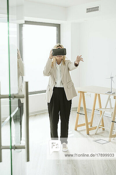 Businesswoman wearing VR goggles in modern office