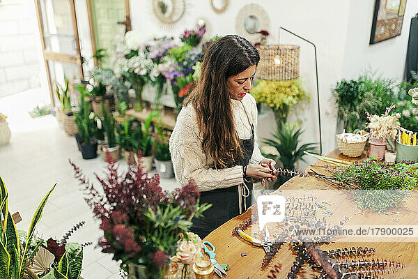 Saleswoman arranging leaves on workbench at floral shop