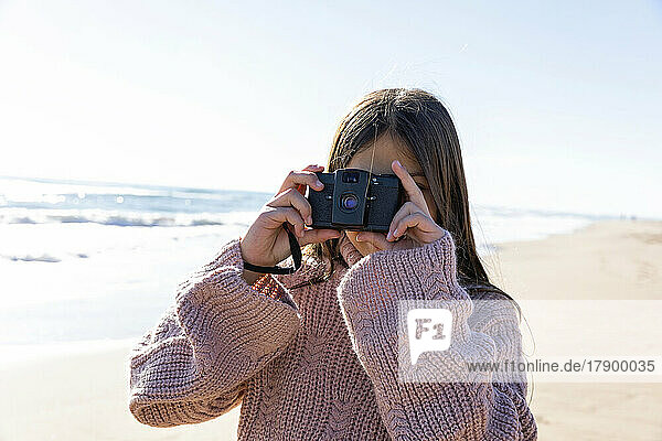Girl with camera taking photos at beach