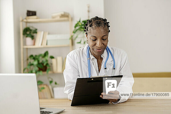 Smiling doctor with clipboard working at home office