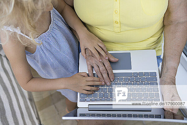 Senior woman using laptop with granddaughter