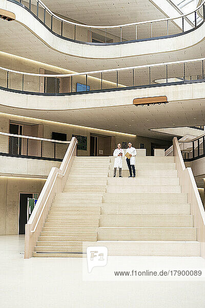 Mitarbeiter des Gesundheitswesens stehen zusammen auf der Treppe in der Lobby des Krankenhauses