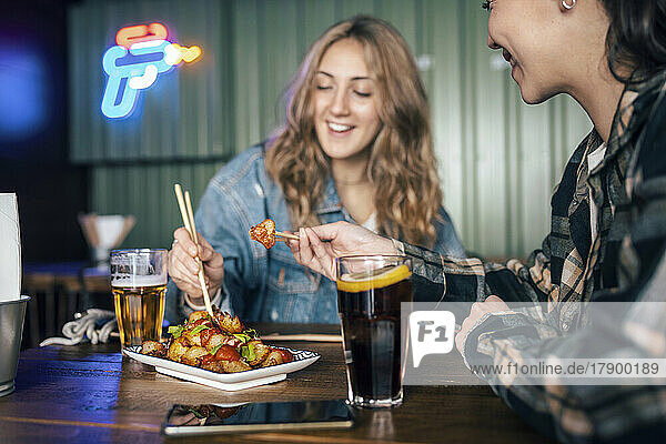 Happy young lesbian couple eating food at restaurant
