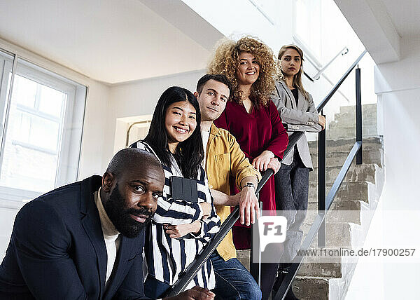 Selbstbewusste junge Geschäftsleute stehen auf der Treppe und schauen in die Kamera