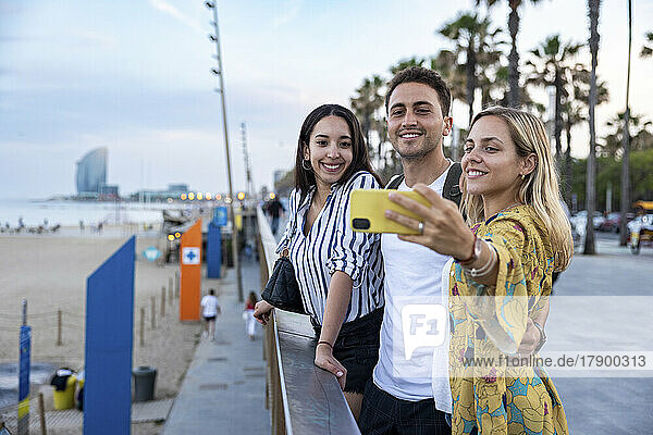 Smiling woman taking selfie with friends at promenade