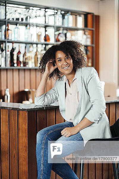 Smiling woman sitting on chair in bar