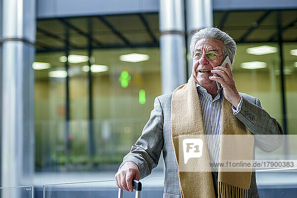 Leitender Geschäftsmann telefoniert vor einer Glaswand