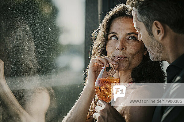Woman having drink with straw looking at boyfriend