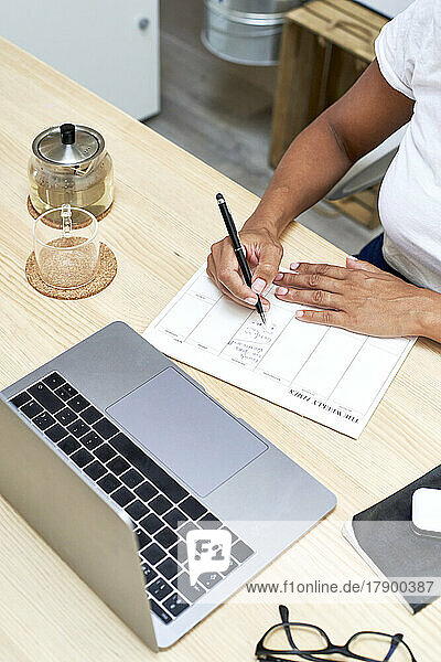 Businesswoman writing in note pad working at home office
