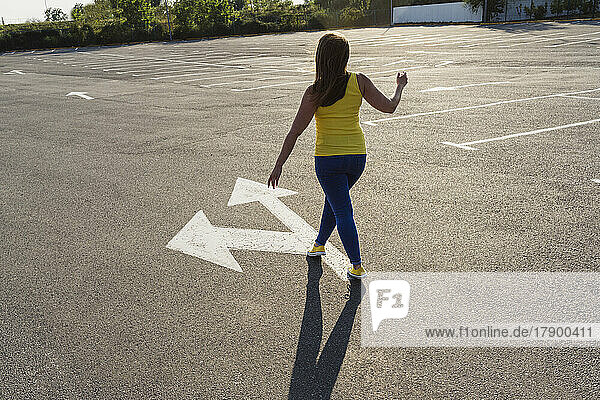 Frau läuft auf Asphalt mit Pfeilsymbol