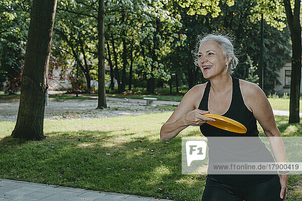 Mature woman having fun playing frisbee in park