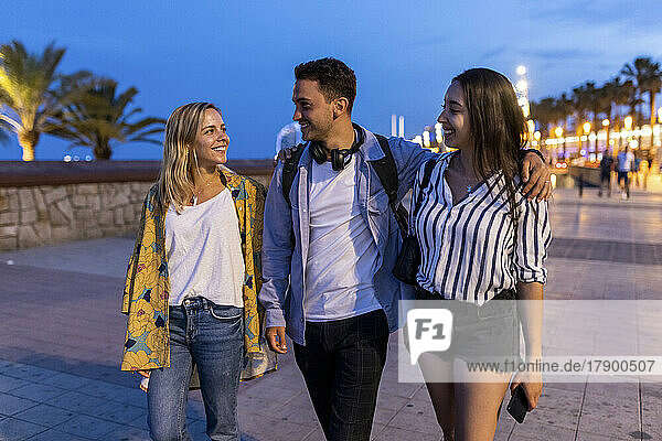 Smiling young man with women walking at promenade