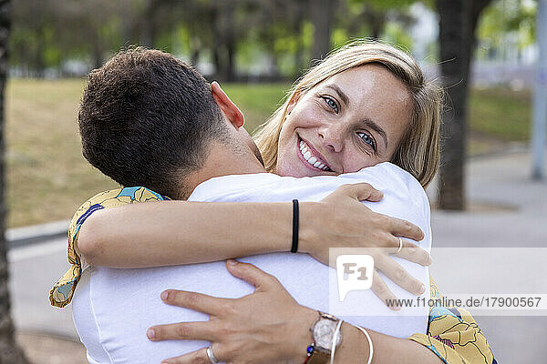 Smiling woman hugging boyfriend at park