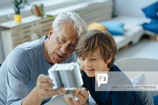 Grandson and grandfather analyzing heating module in living room