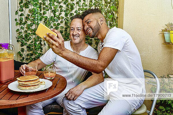 Gay couple taking selfie through smart phone