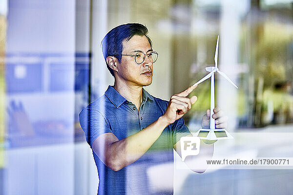 Man examining wind turbine model seen through glass