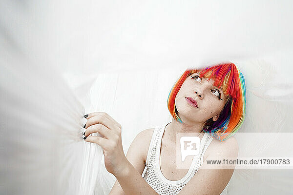 Woman with multi colored dyed hair surrounded by plastic foil