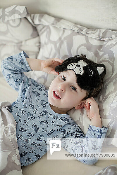 Junge mit schlafender Augenmaske liegt auf dem Bett