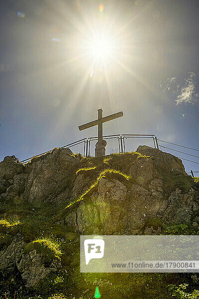 Deutschland  Bayern  Sonne scheint über dem Gipfelkreuz am Nebelhorn