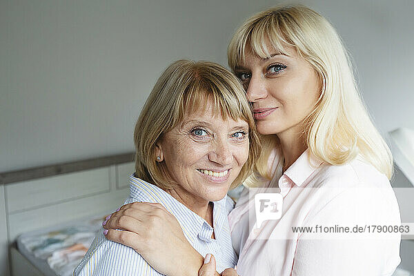 Lächelnde blonde Frau umarmt und fürsorglich ihre Mutter zu Hause