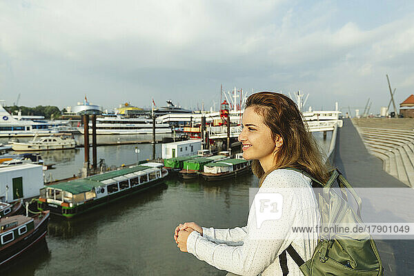 Happy woman standing by railing at Port of Hamburg  Germany