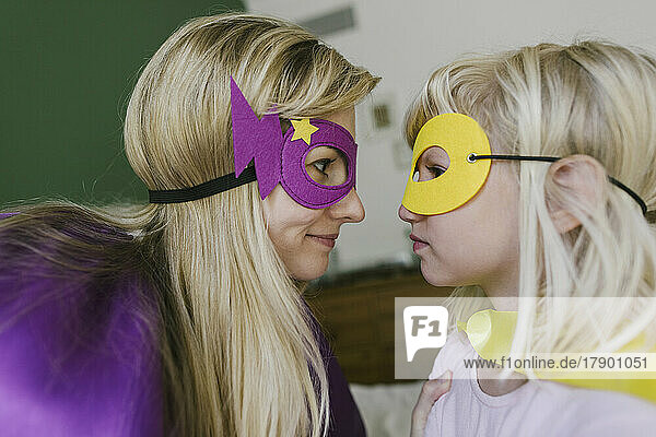 Mutter und Tochter in Umhang und Maske schauen einander an