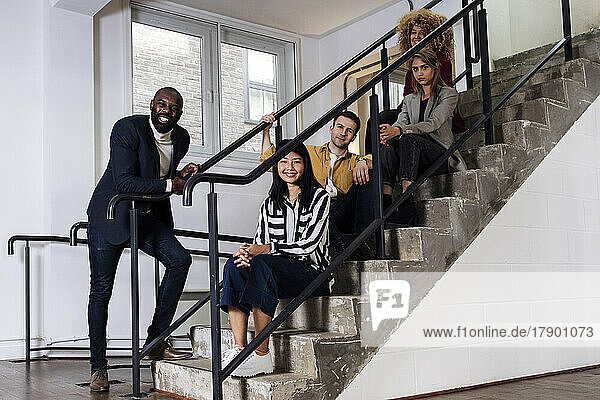 Gruppe junger Geschäftsleute sitzt auf Treppen in Büroräumen