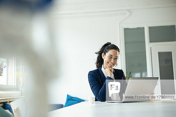 Happy businesswoman with laptop on table