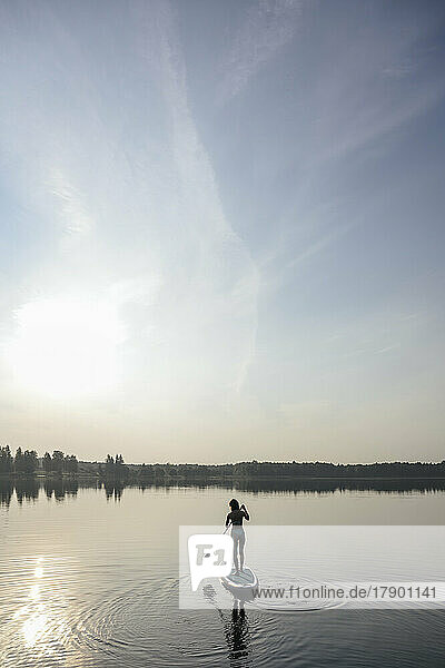Woman doing standup paddleboarding in lake