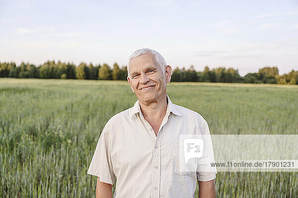 Lächelnder älterer Bauer steht auf dem Bauernhof