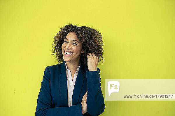 Cheerful businesswoman in front of green wall