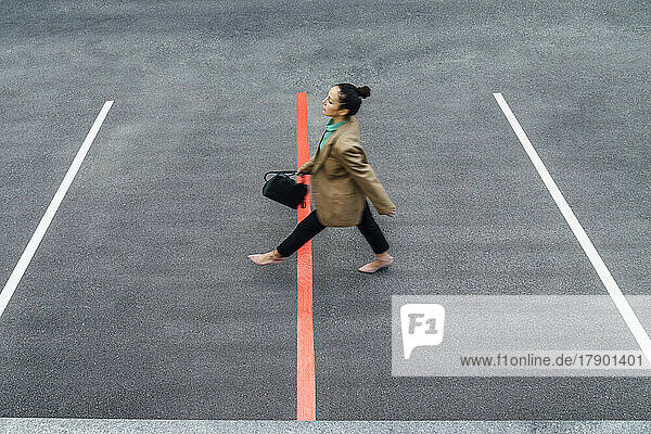 Businesswoman walking over red line at parking lot