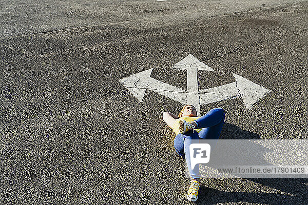 Frau entspannt sich in der Nähe eines Drei-Wege-Richtungspfeilzeichens auf der Straße