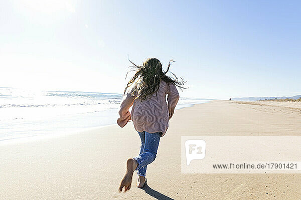 Girl running at beach on sunny day