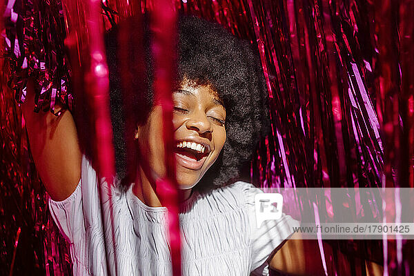 Carefree young woman amidst tinsels enjoying at party