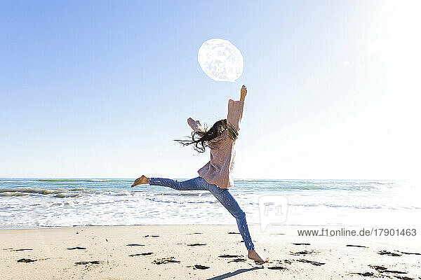 Mädchen springt mit Ballon am Strand