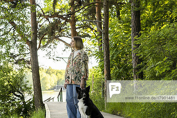 Thoughtful young woman standing by dog in park