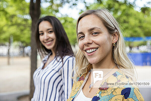 Happy blond woman with friend at park