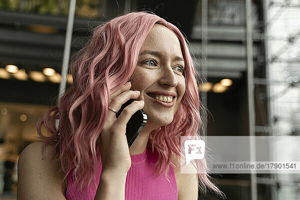 Glückliche Frau mit rosa Haaren  die mit dem Handy spricht