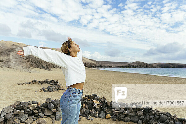 Young woman with arms outstretched enjoying weekend at beach