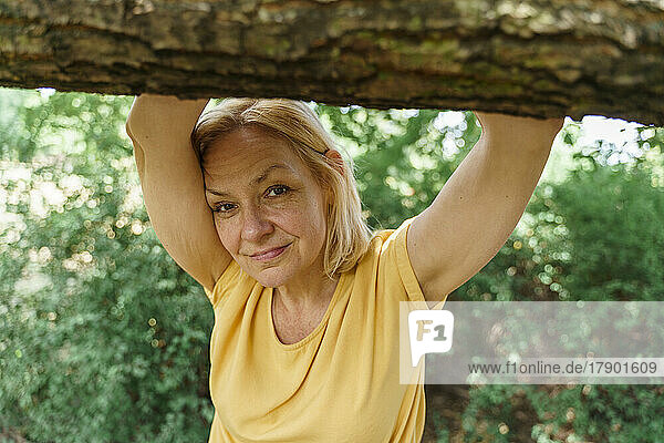 Smiling mature woman standing with arms raised at park