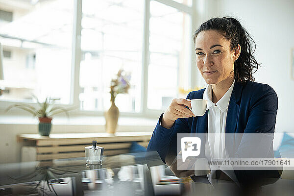 Smiling businesswoman having coffee at table