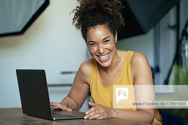 Businesswoman with laptop laughing at table in office