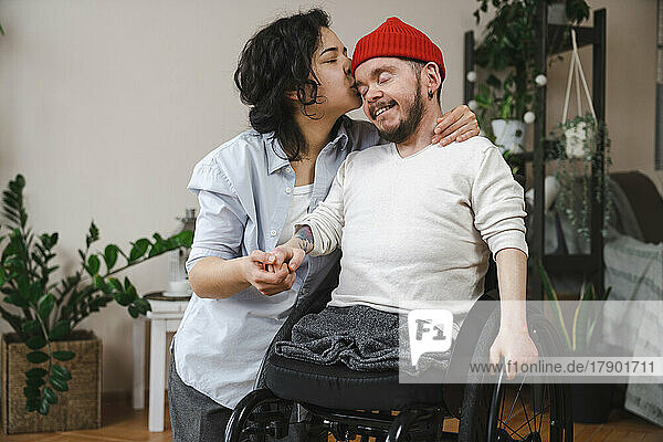 Frau küsst Freund mit Behinderung zu Hause auf den Kopf